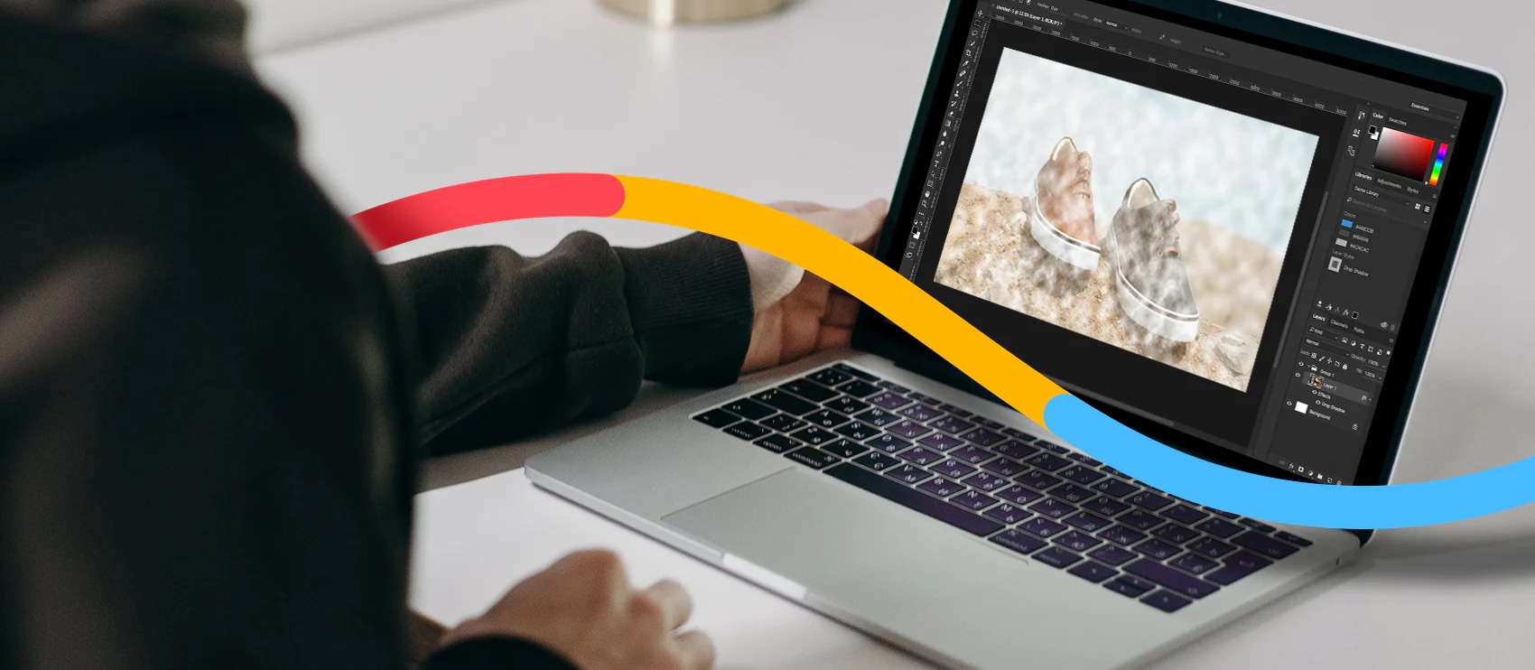 Close-up of hands working on a laptop displaying video editing software on a desk with yellow cable beside it