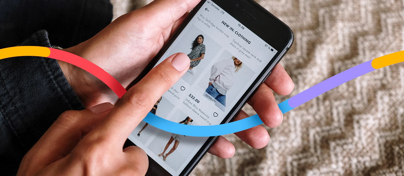 Person browsing a fashion app on a smartphone, displaying new clothing items with colorful design accents.