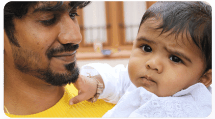 A man holding a baby, representing Path's commitment to community support by reinvesting revenue into life-changing initiatives.